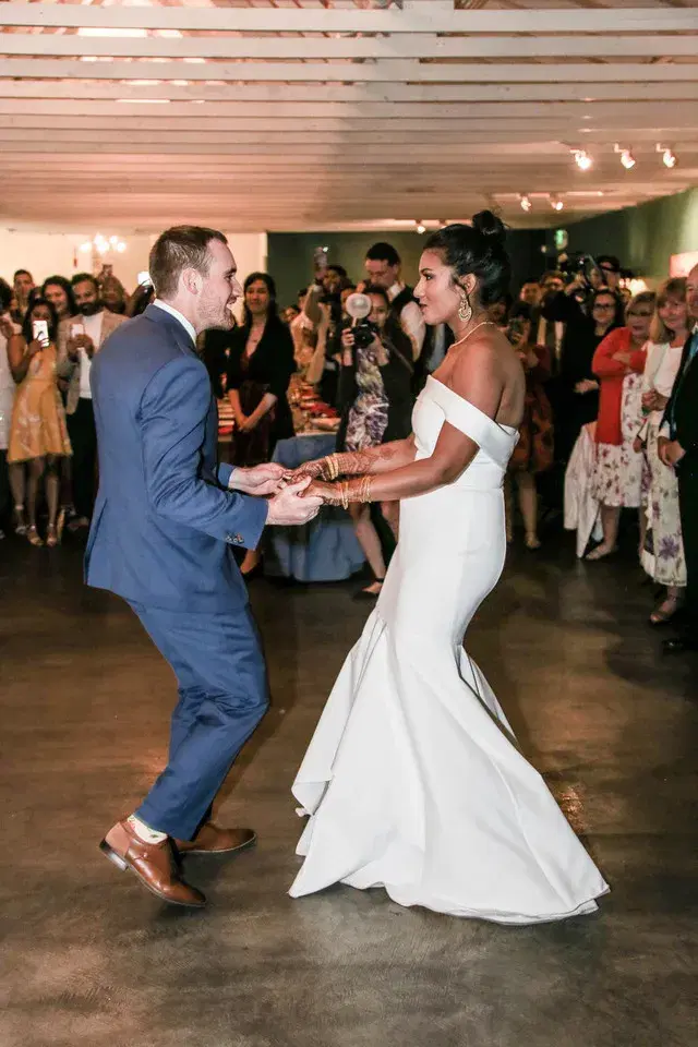 Bride and groom sharing an upbeat first dance surrounded by guests at their wedding reception