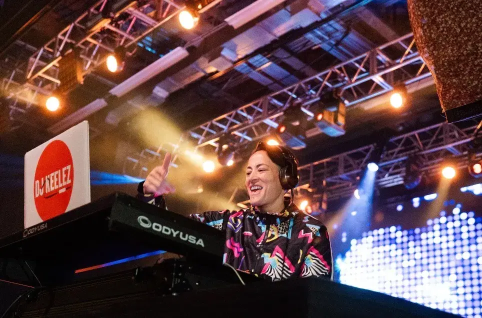 DJ Keelez mixing on stage with concert lighting at a Los Angeles corporate event