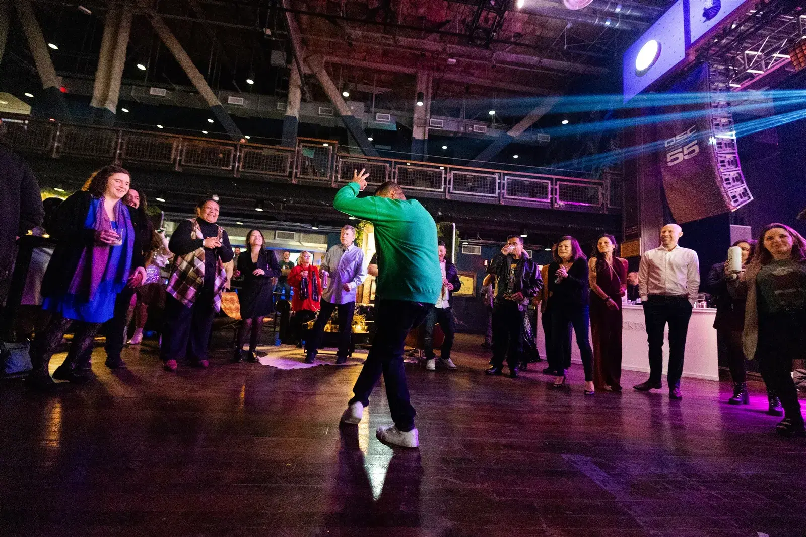 Employee dancing in a circle of cheering coworkers at a corporate holiday party in a Los Angeles venue
