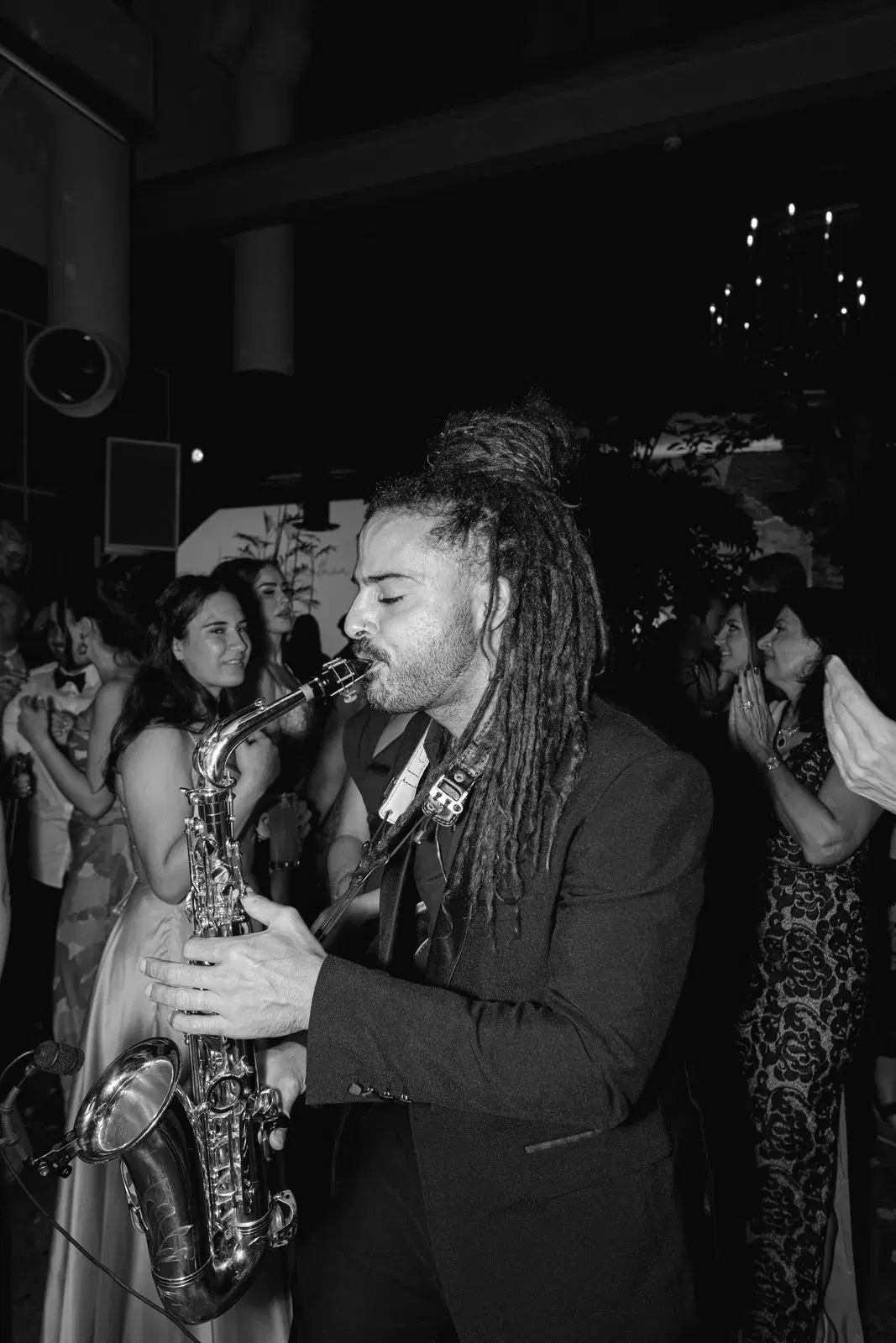Live saxophone player performing among guests on the dance floor at a wedding reception