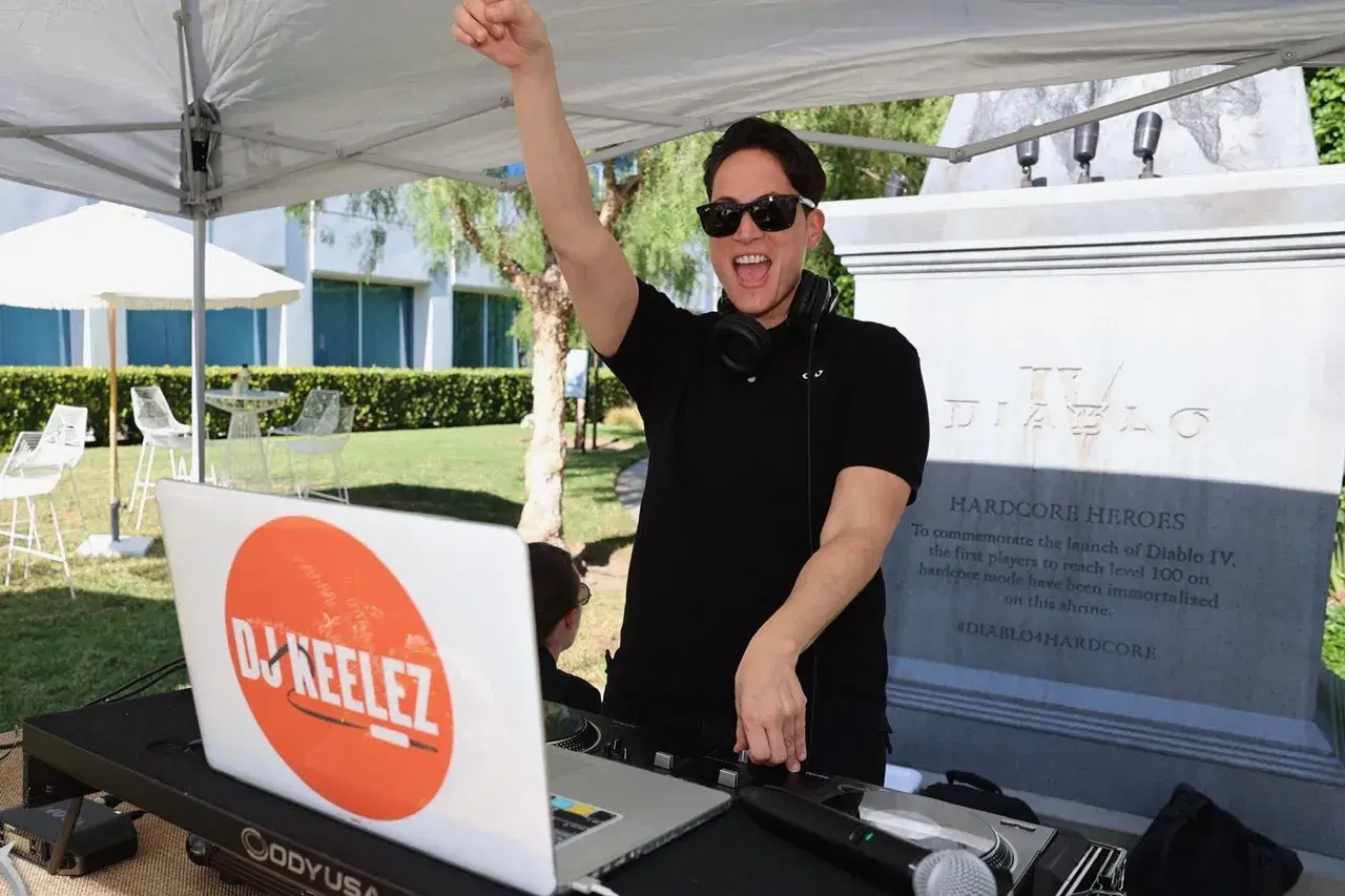 DJ Keelez cheering behind her decks at an outdoor Diablo IV brand activation event