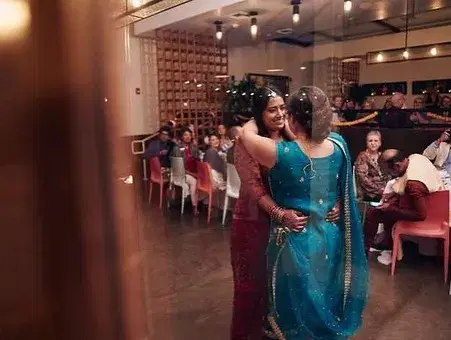 South Asian wedding couple on their first dance as guests cheer from the sidelines