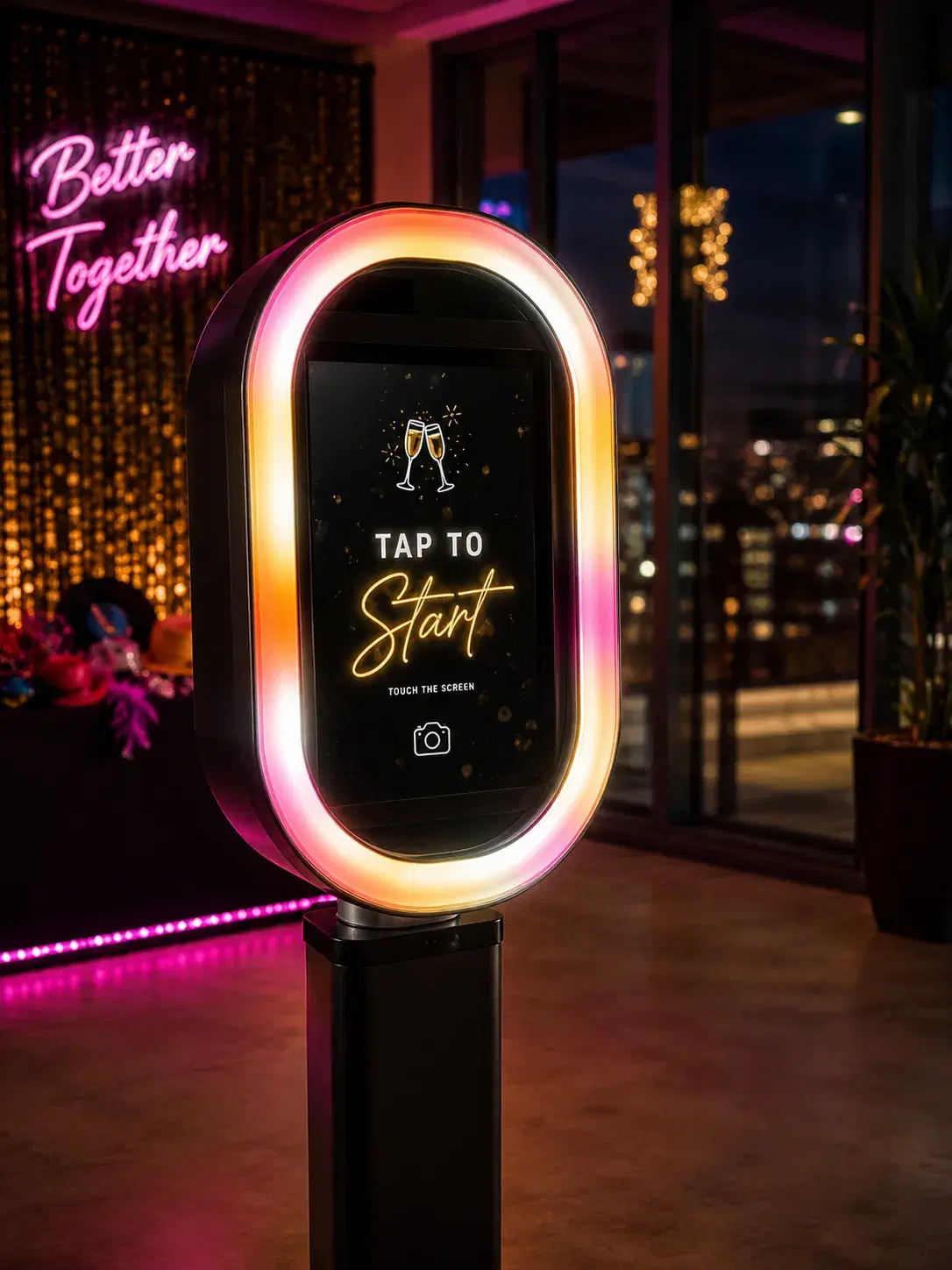 Illuminated open-air photo booth kiosk with tap-to-start screen in front of a Better Together neon sign