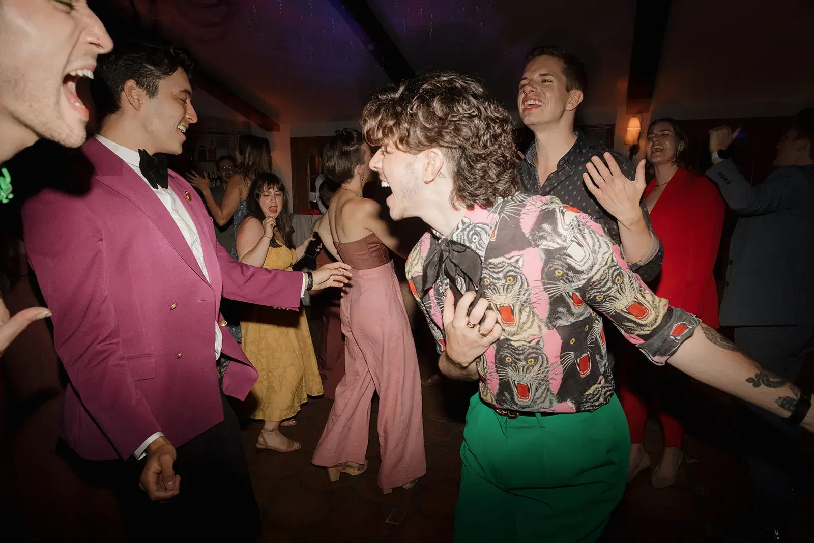Guests in colorful outfits laughing and dancing at a lively company party in Los Angeles