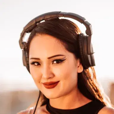 DJ Mish in headphones at sunset during a rooftop set