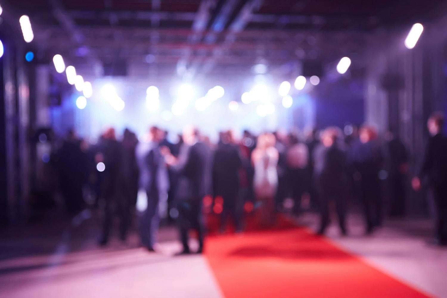 a group of people standing outside a wedding blurred on a red carpet