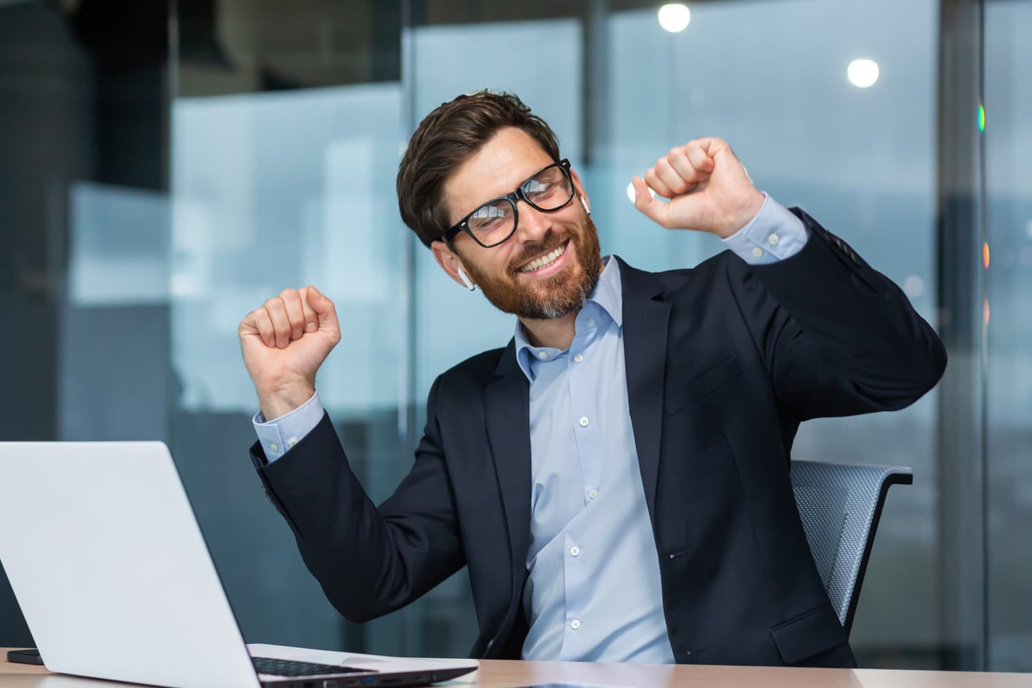 White man with arms raised in front of laptop